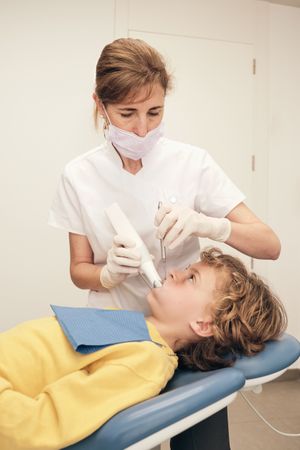 Dentist scanning teeth of boy