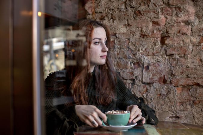 Woman sitting calmly in cafe with warm drink