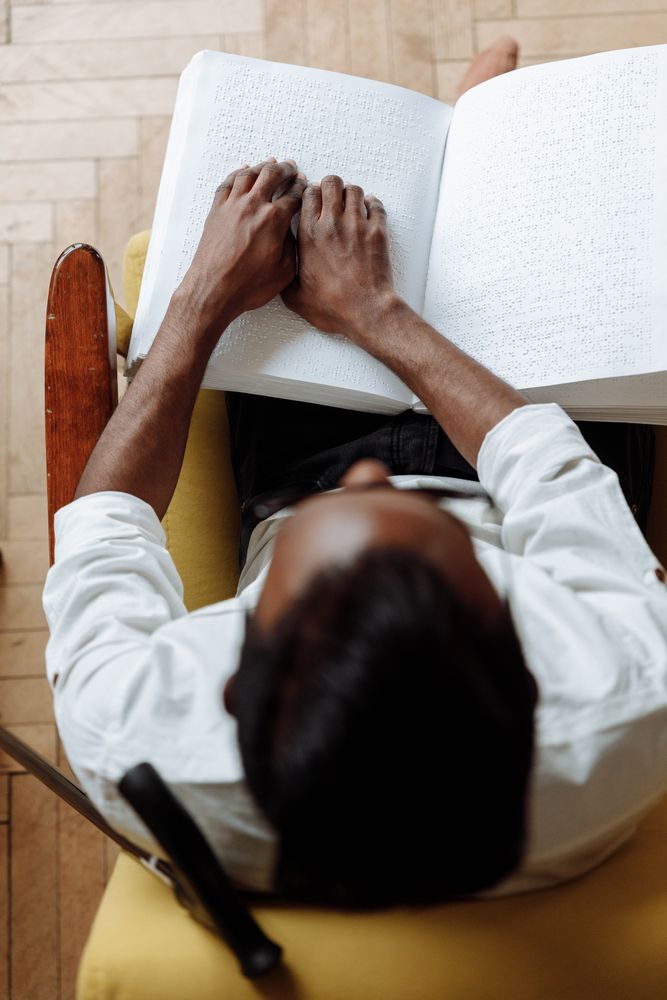 Top view of a visually challenged young man reading using braille system