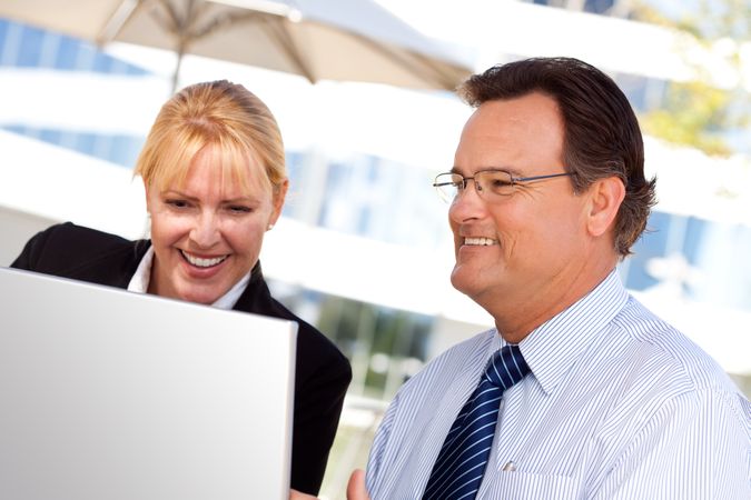 Businessman and Female Colleague Using Loptop Outdoors