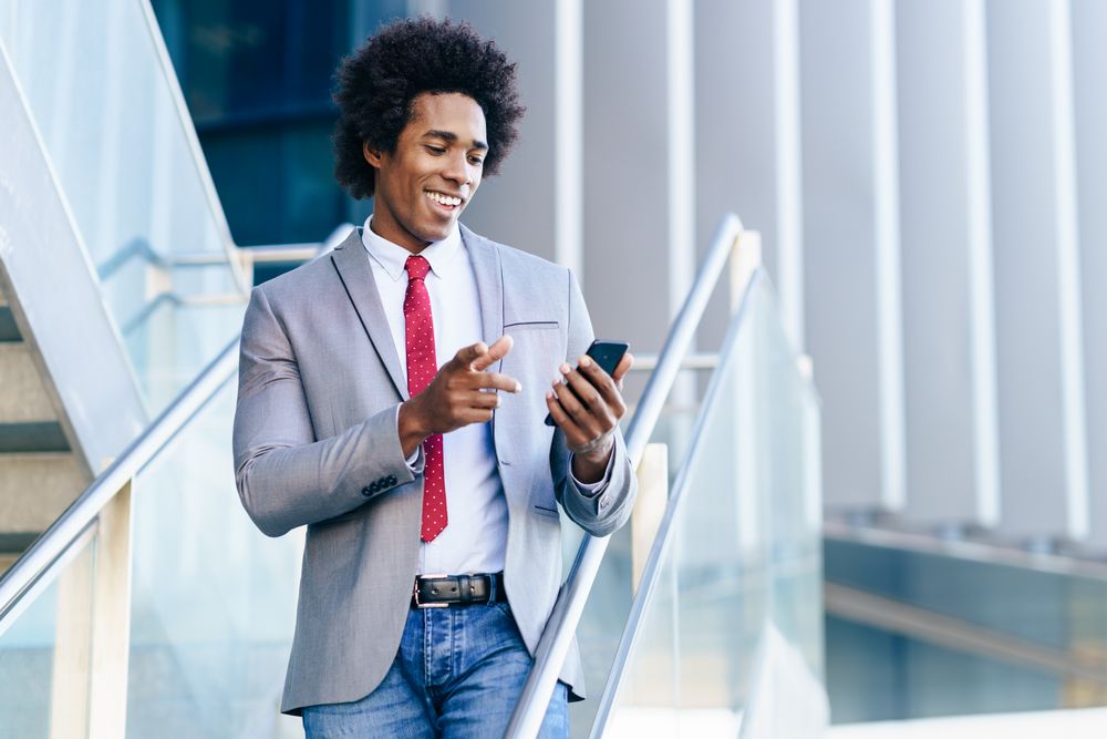 Smiling man in business casual on stairs checking his phone