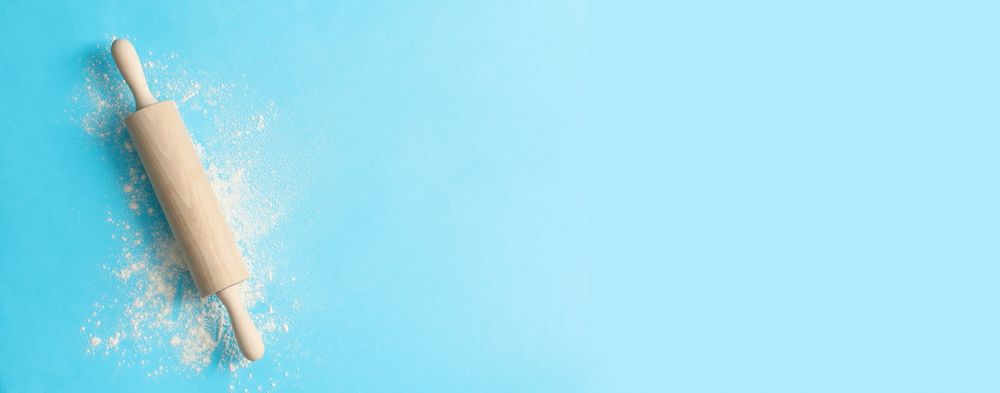 Rolling pin and flour on blue background