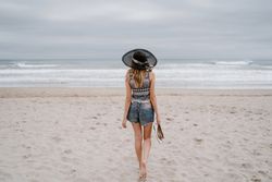 Young female walking barefoot on sandy beach