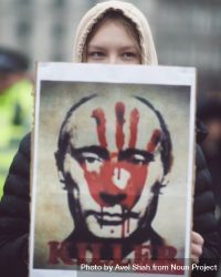 London, England, United Kingdom - March 5 2022: Woman holding sign of Putin’s face with red hand 4OoOL4