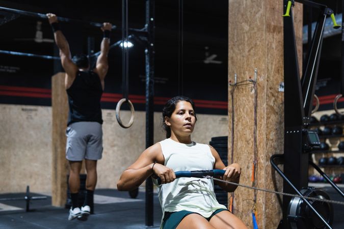 Hispanic sportswoman exercising on rowing machine
