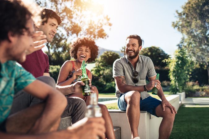 Group of friends hanging out and having beers together outdoors