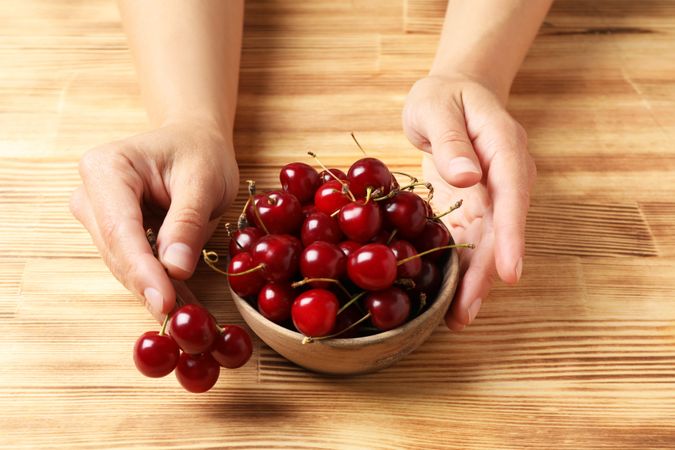 Ripe cherry fruits in a bowl on a wooden background