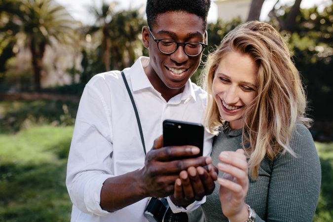 Young man and woman looking at photos on mobile phone
