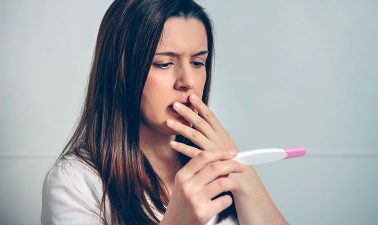 Pregnant looking at a pregnancy test