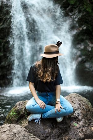 Smiling woman sitting near waterfall