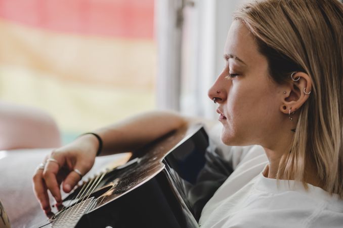 Woman playing guitar on bed