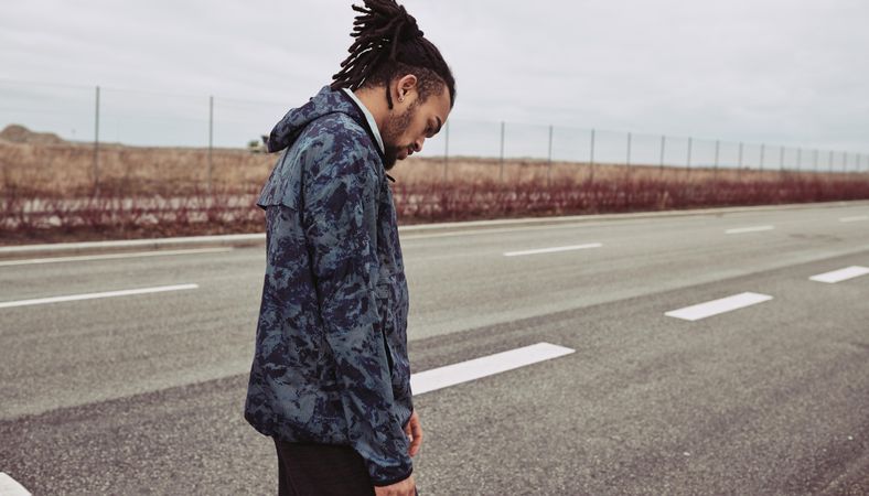 Male dressed in warm activewear standing on an empty road before jog