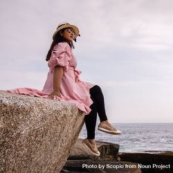 Woman in pink long sleeve shirt sitting on rock on seashore 0PmO75