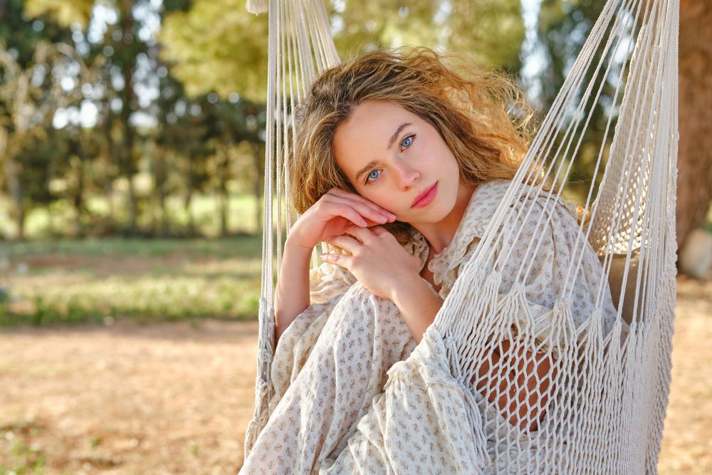 Young female touching face on hammock