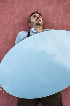Man lying down holding mirror with reflection