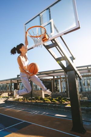 Woman slam dunking basketball