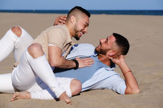 Affectionate gay couple relaxing on beach