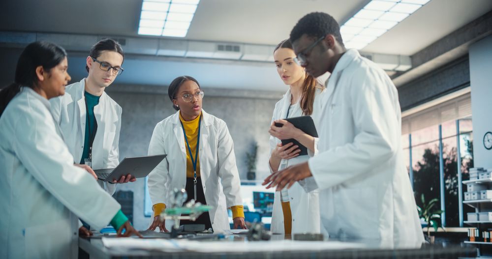 Diverse Team of Industrial Robotics Specialists Gathered Around a Table to Discuss a Blueprint