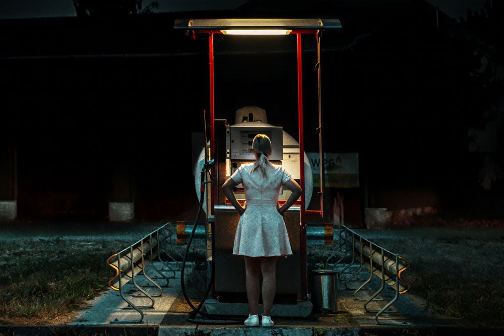 Lone Woman Standing at a Gas Station Under the Night Sky