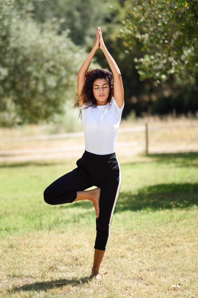 Arab woman doing one legged yoga pose in park
