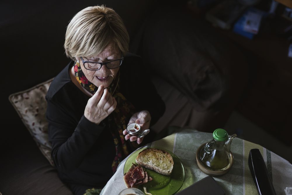 Mature woman eating tablet from pill box