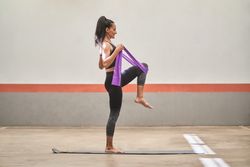 Adult female athlete stretching leg with resistance band