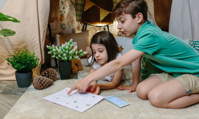 Children playing treasure hunting game in a diy tent at home
