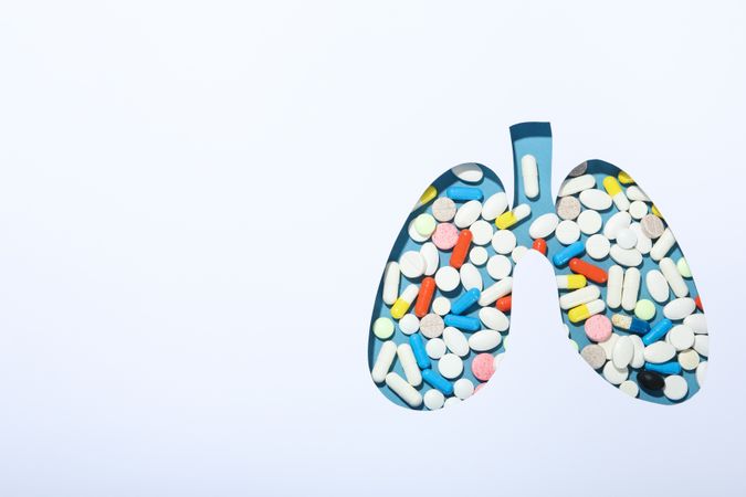 Lung shape cut out of paper with pills underneath with copy space