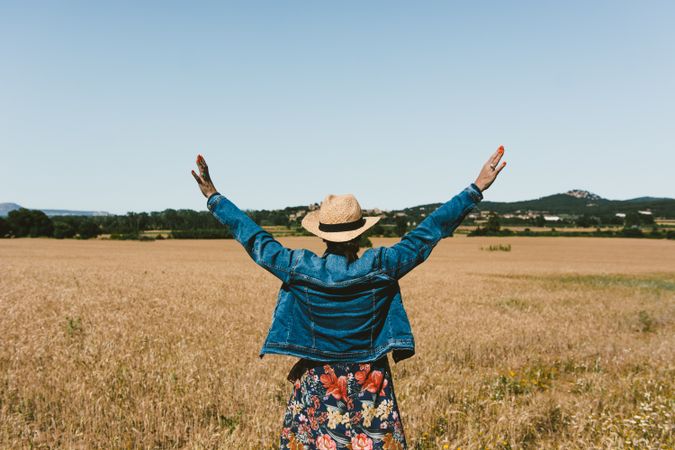 Female farmer with hat looking at her wheat crop.
