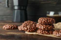 Chocolate cookies and cup of coffee on wooden table against dark background, space for text