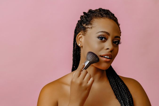 Black woman with make up brush to her cheek, copy space