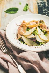 Close-up of ham and pear in bowl, with fork on linen napkin
