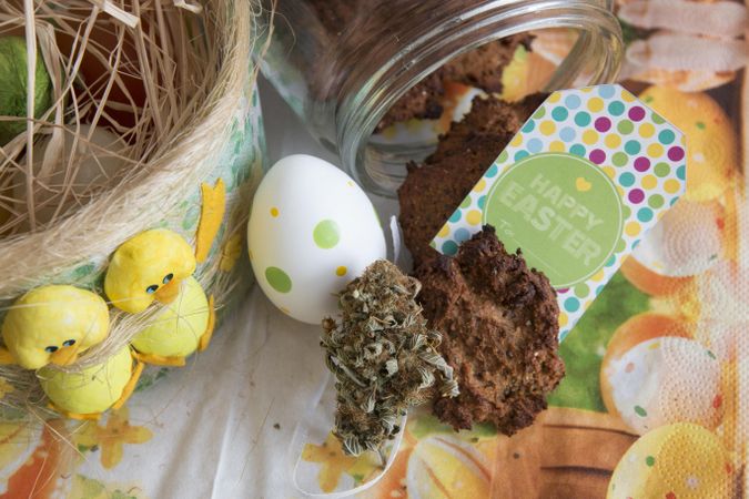 Top view of dried marijuana bud and cookies with Easter decorations