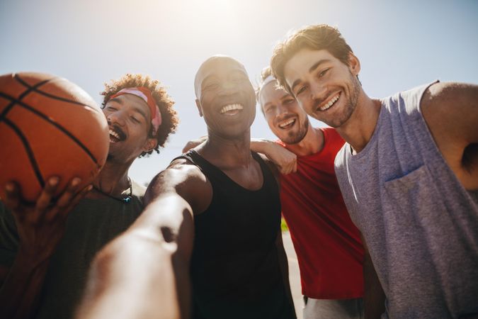 Four men posing for selfie holding a basketball