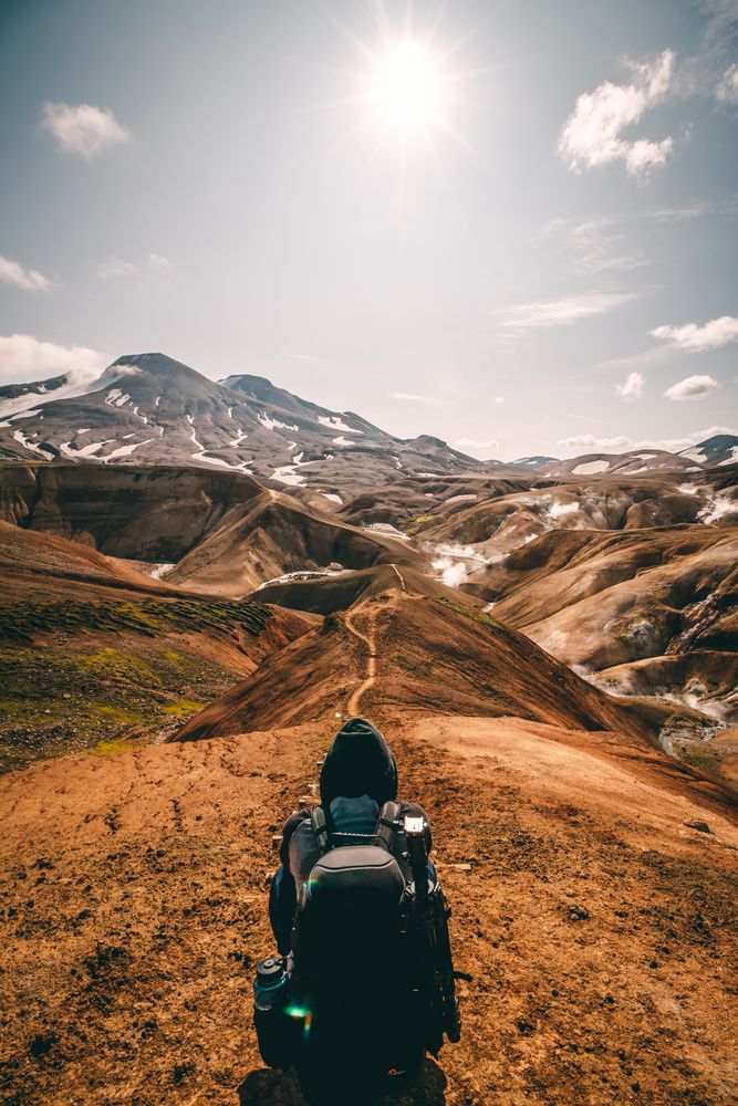 Person with backpack hiking in the mountain during daytime