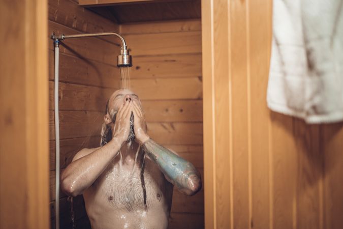 Man taking shower in wooden bathroom
