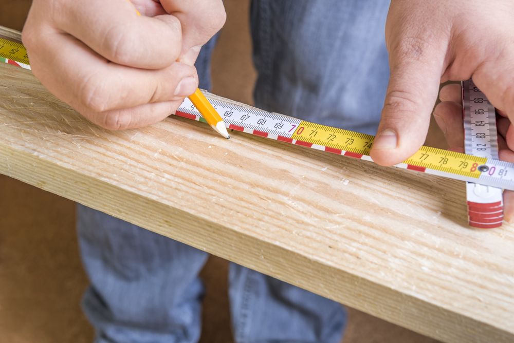 Carpenters hands with pencil and measuring tape