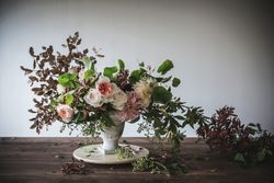 Composition of flowers and plants in vintage vase on board