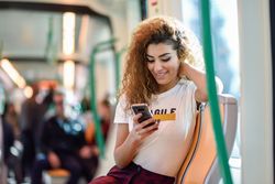 Arab woman sitting in train carriage texting on phone