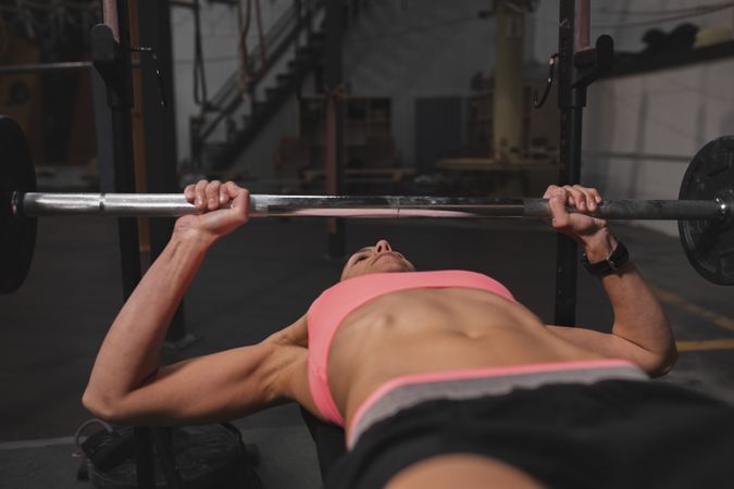 Athletic woman training with barbells in gym