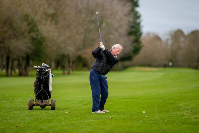 Man swinging golf club down the green on course