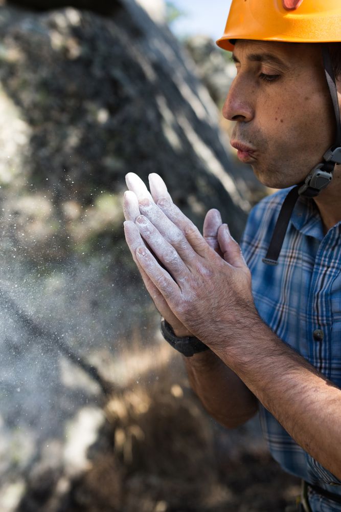 Climber blows chalk powder from his hands