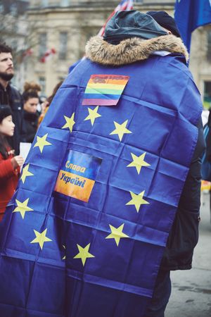 London, England, United Kingdom - March 5 2022: Man draped in EU flag with Ukrainian & rainbow flag
