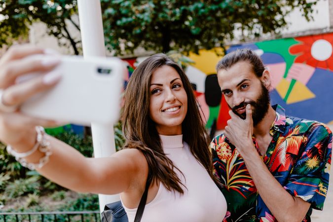 Trendy couple taking selfie on city street