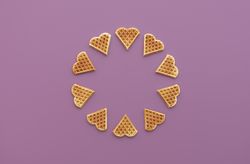 Heart shaped waffles top view on a purple background