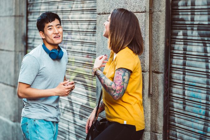 Joyful multiracial friends talking while standing on city street