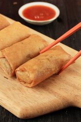Close up of chopsticks reaching for Chinese egg rolls