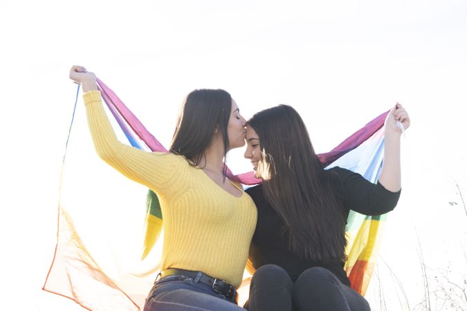 Young female couple with gay pride flag