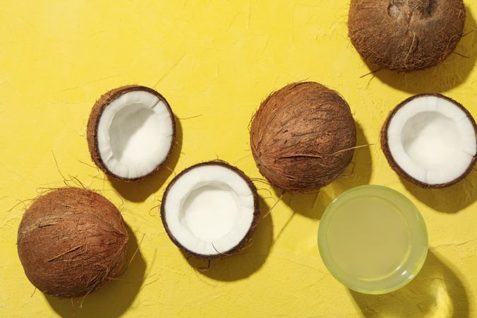 Coconut and water on yellow background, top view. Tropical fruit