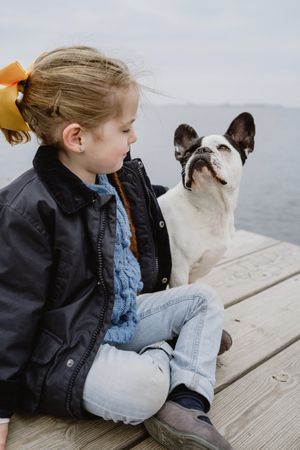 young girl with dog on pier